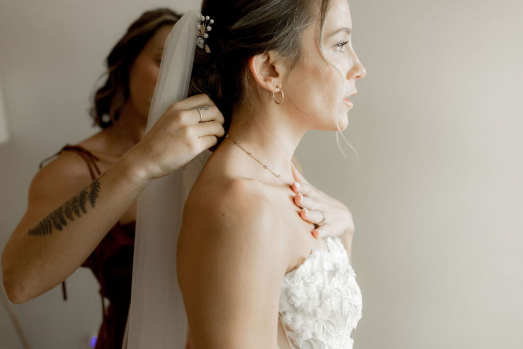 Bridesmaids helping wear necklace 